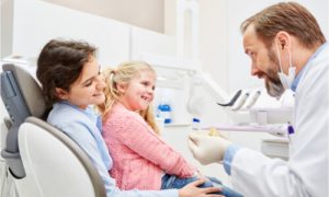a pediatric dentist with a happy conversation with a little girl