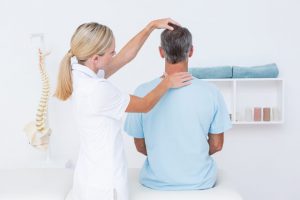 The chiropractor checks the neck and spine of the patient.